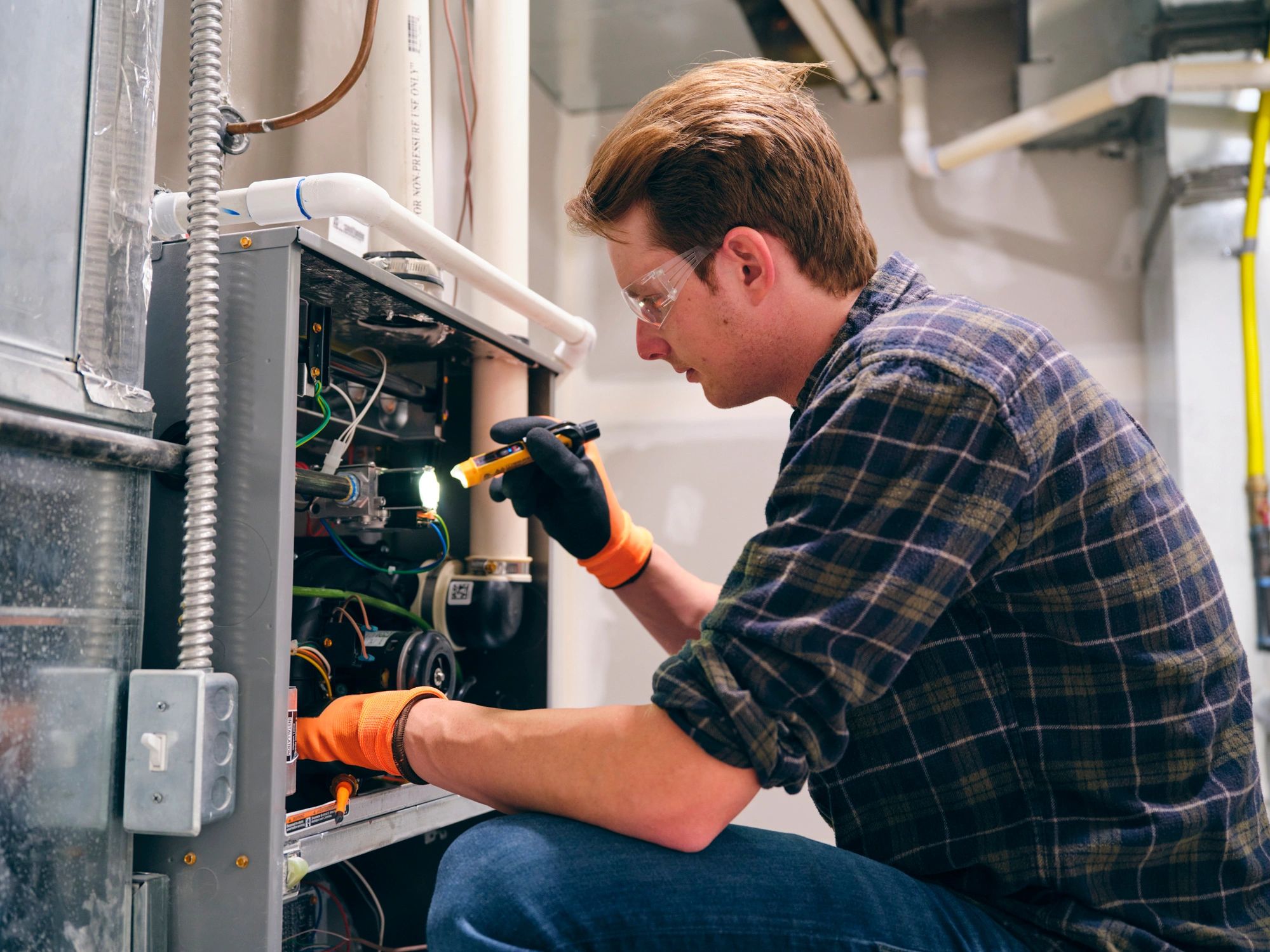 Technician inspecting a residential HVAC furnace for performance and safety